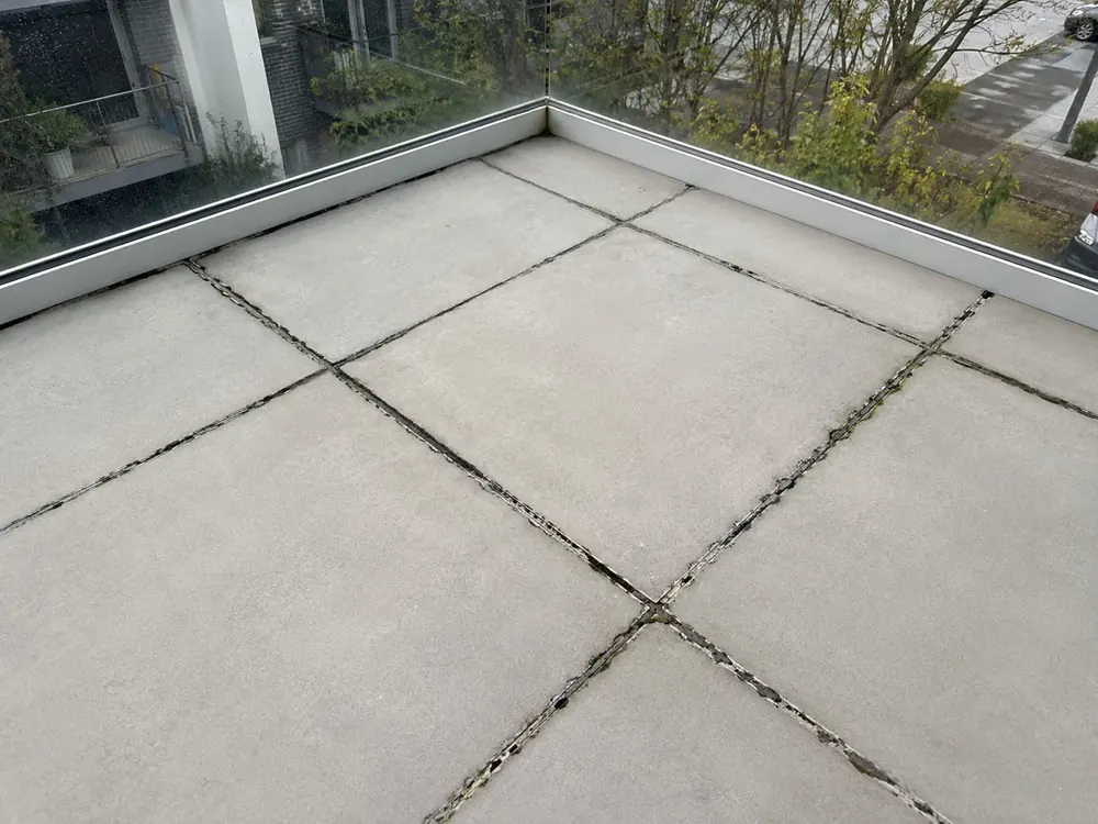 Balcony tiles with cracked and mouldy grout before regrouting